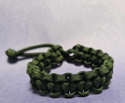 Green braided bracelet on a light gray background