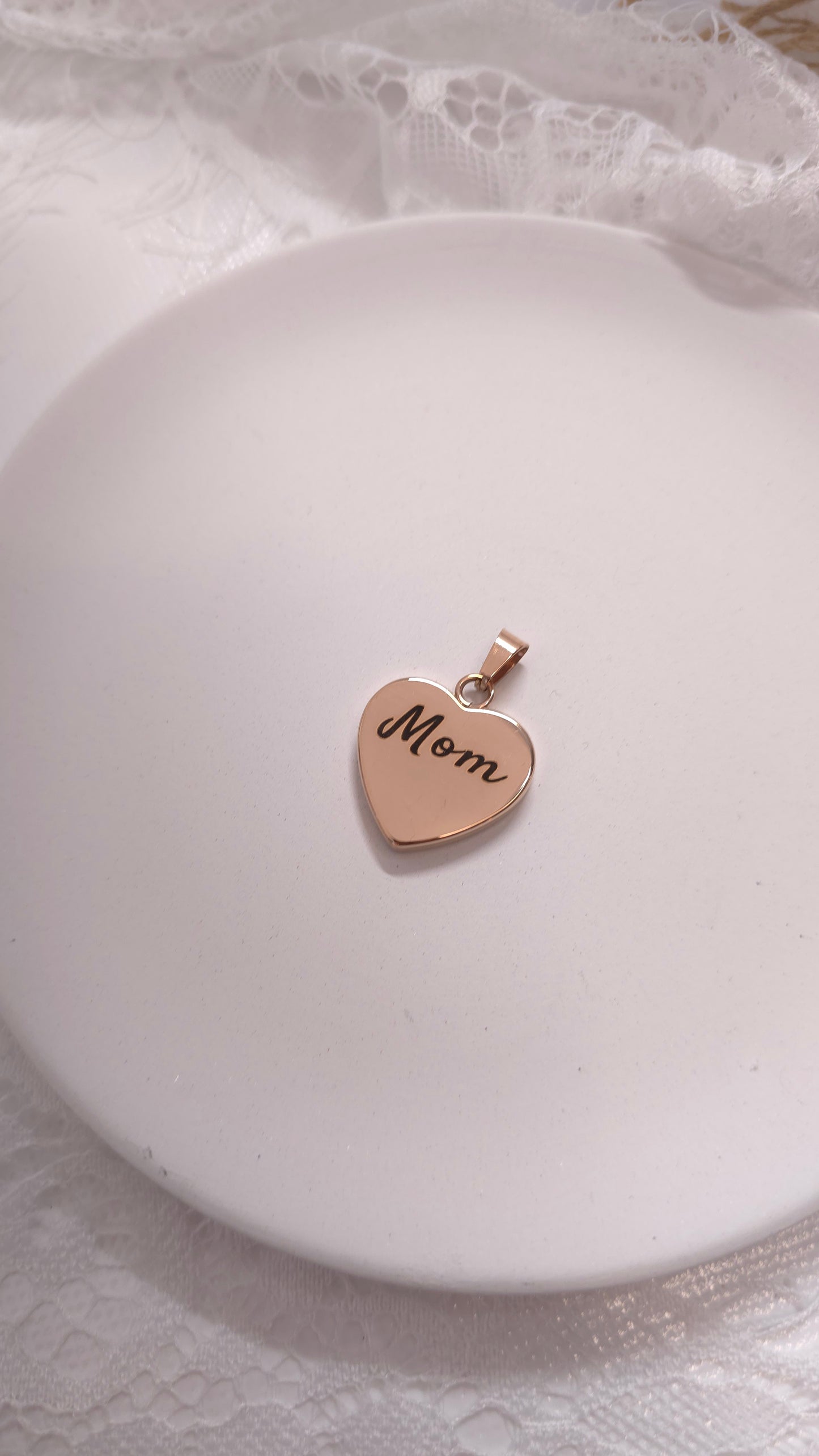 Heart-shaped pendant with 'Mom' engraving on a white dish