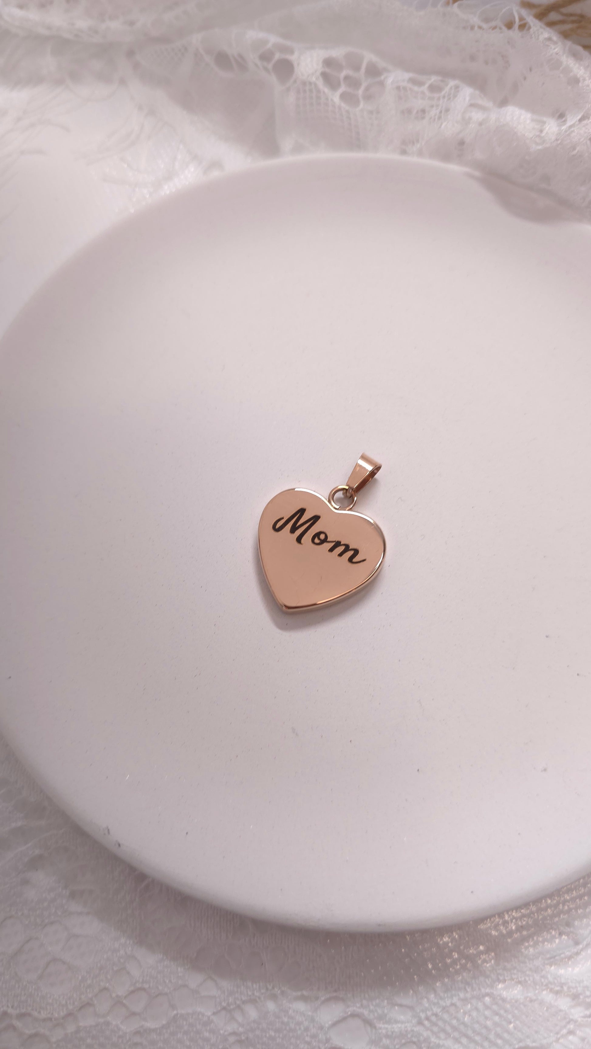 Heart-shaped pendant with 'Mom' engraving on a white dish